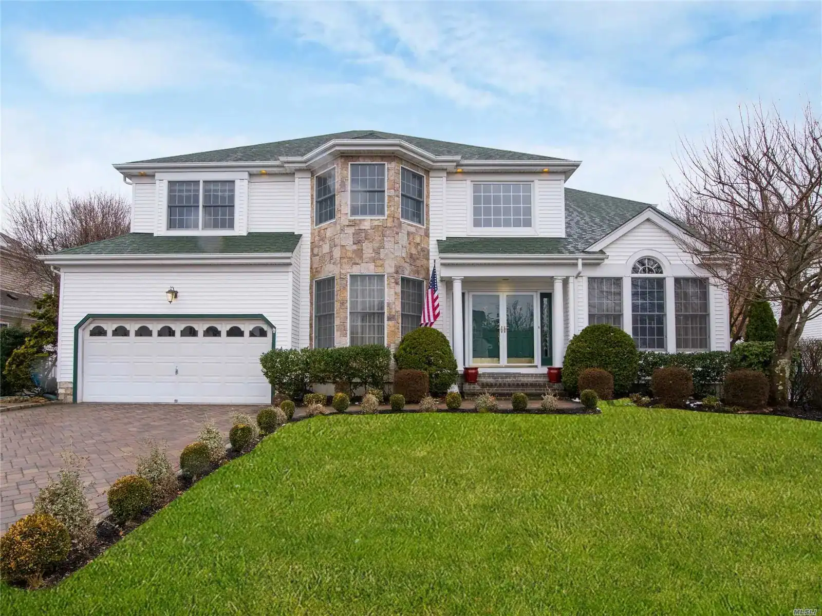 Beautiful two-story house with a manicured lawn and stone accents in Long Island.