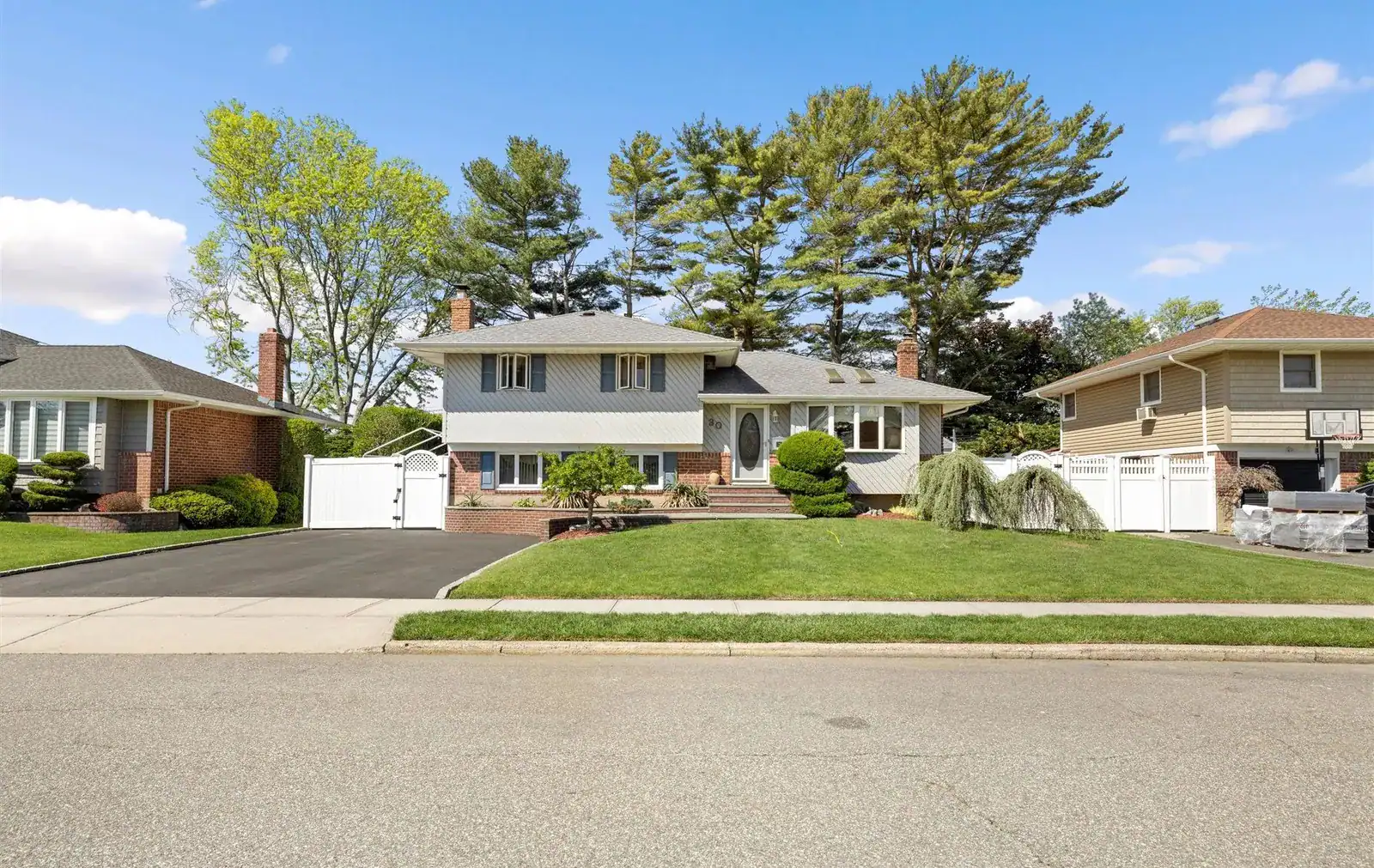 Beautiful suburban house in Long Island with lush greenery and clear blue sky.